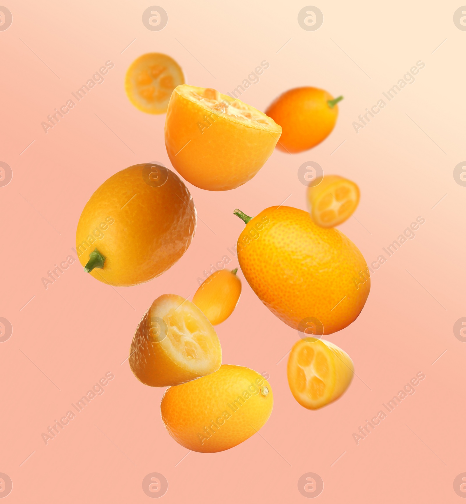 Image of Delicious whole and cut kumquats falling on color background