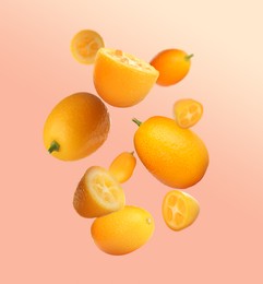 Image of Delicious whole and cut kumquats falling on color background