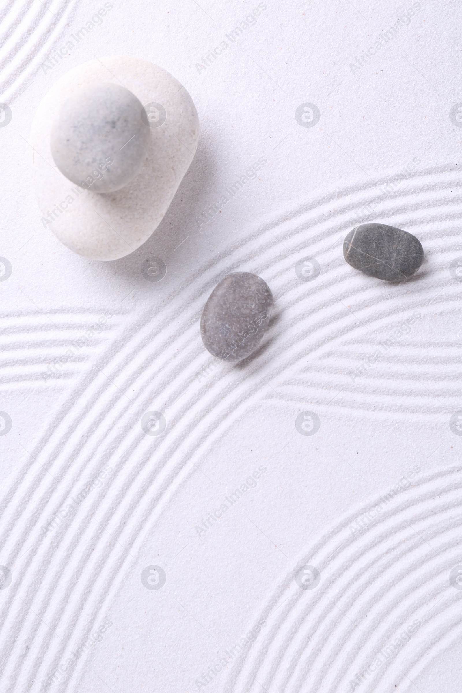 Photo of Zen garden stones on white sand with pattern, flat lay. Space for text