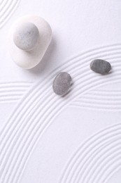 Photo of Zen garden stones on white sand with pattern, flat lay. Space for text