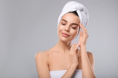 Photo of Happy young woman with towel on head against light grey background. Washing hair