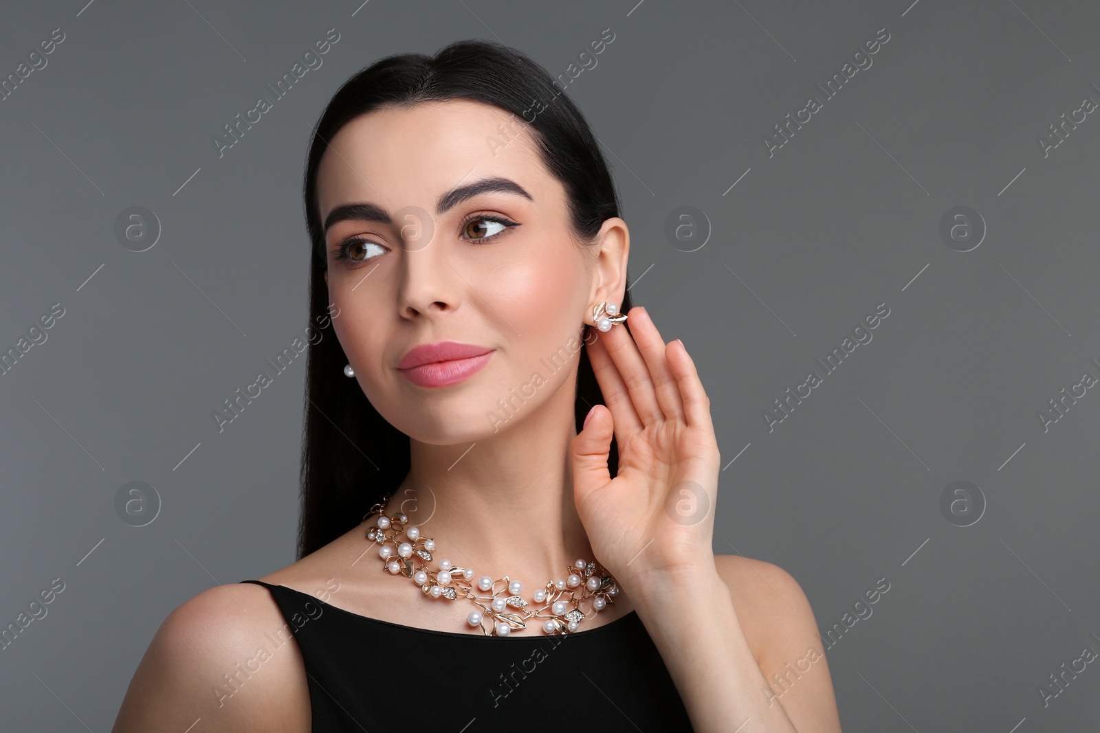 Photo of Beautiful young woman with elegant jewelry on dark grey background