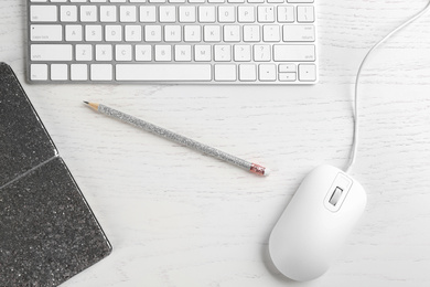 Flat lay composition with mouse and keyboard on white wooden table