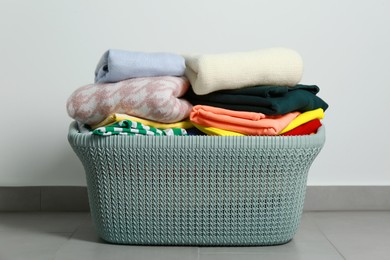 Plastic laundry basket with clean clothes on floor indoors