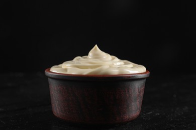 Photo of Fresh mayonnaise sauce in bowl on black table, closeup