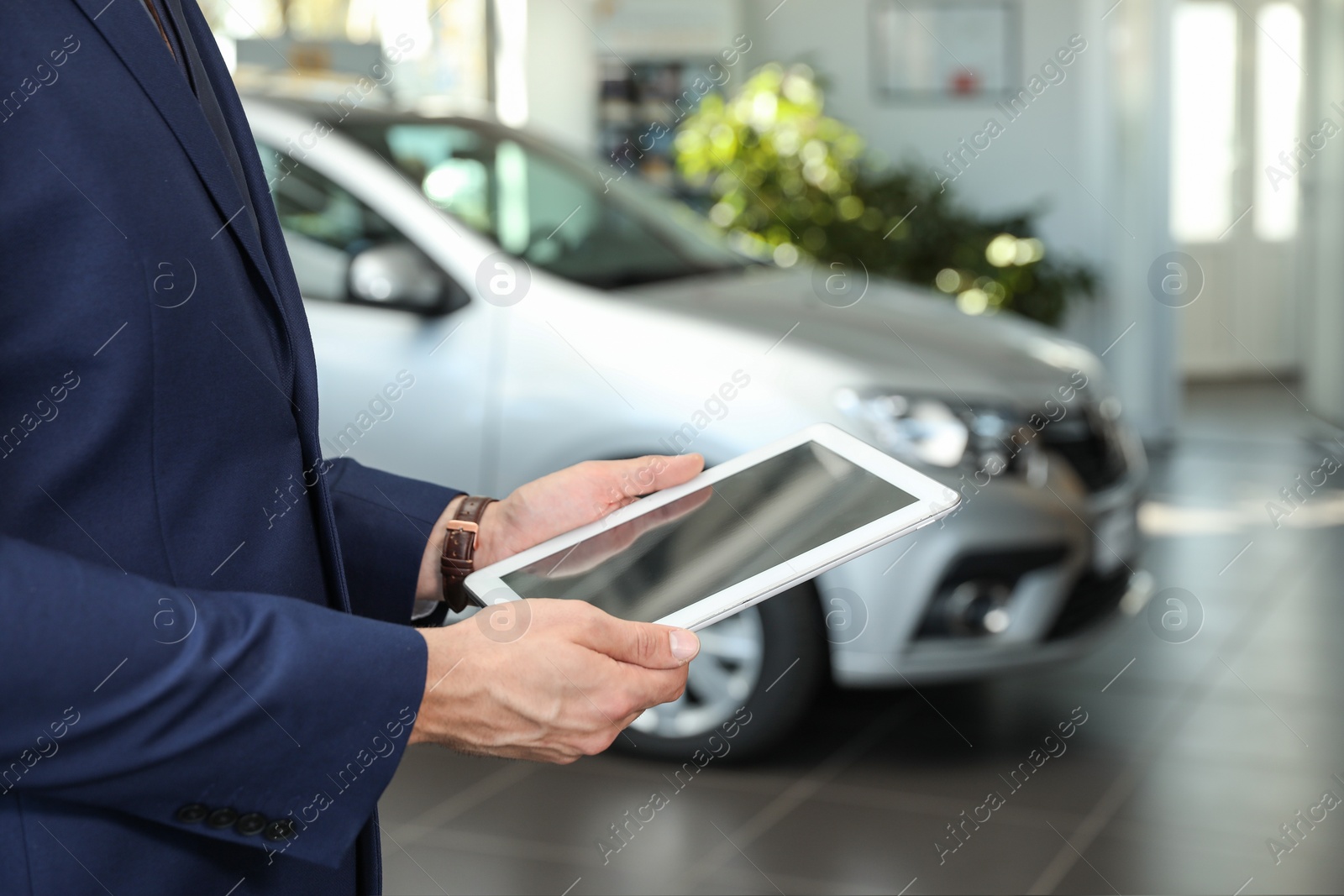 Photo of Young car salesman with tablet in dealership, closeup