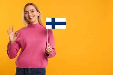 Image of Happy young woman with flag of Greece showing OK gesture on yellow background