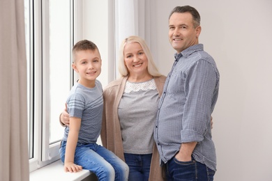 Happy senior couple with little grandson near window at home