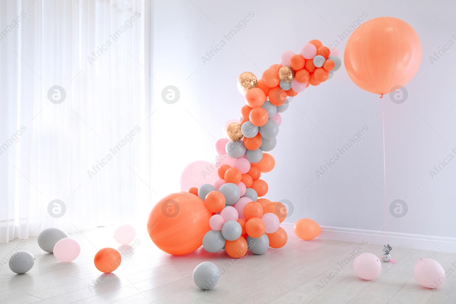 Image of Balloon garland near white wall in room. Festive decor