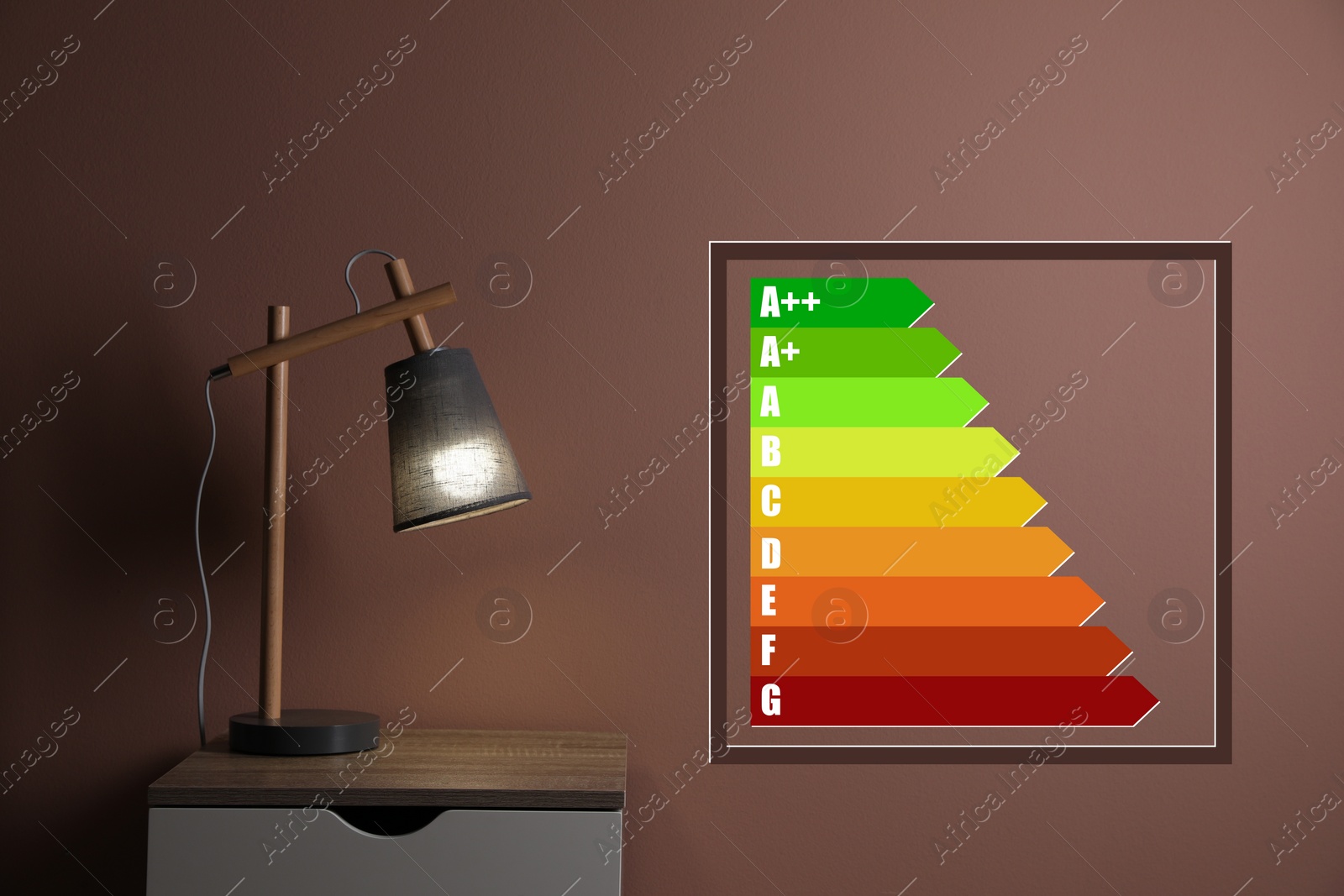 Image of Energy efficiency rating label and lamp on wooden bedside table near brown wall indoors