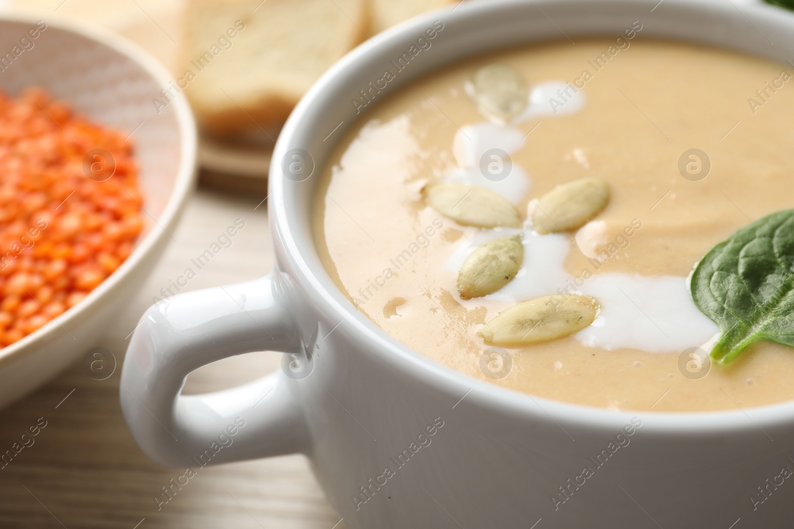 Photo of Healthy cream soup high in vegetable fats on wooden table, closeup