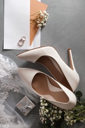 Photo of Flat lay composition with wedding rings, white high heel shoes and veil on grey background