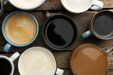 Photo of Different coffee drinks in cups on wooden table, flat lay