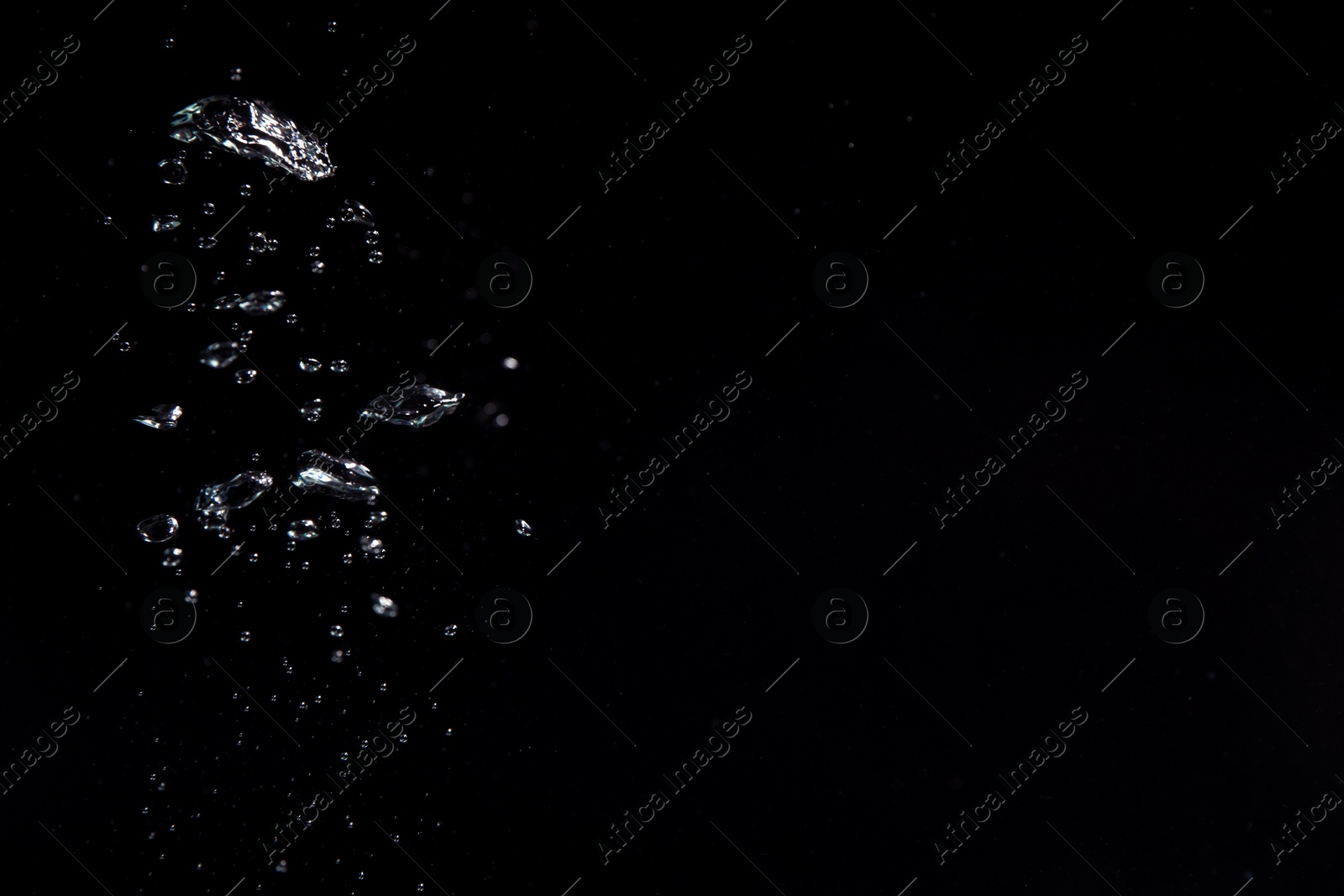 Photo of Air bubbles in water on black background, space for text