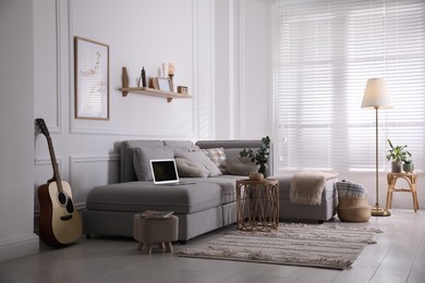 Photo of Living room with comfortable grey sofa and stylish interior elements near window