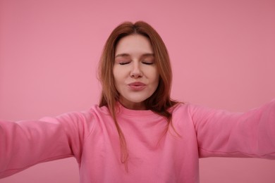 Photo of Beautiful woman taking selfie on pink background