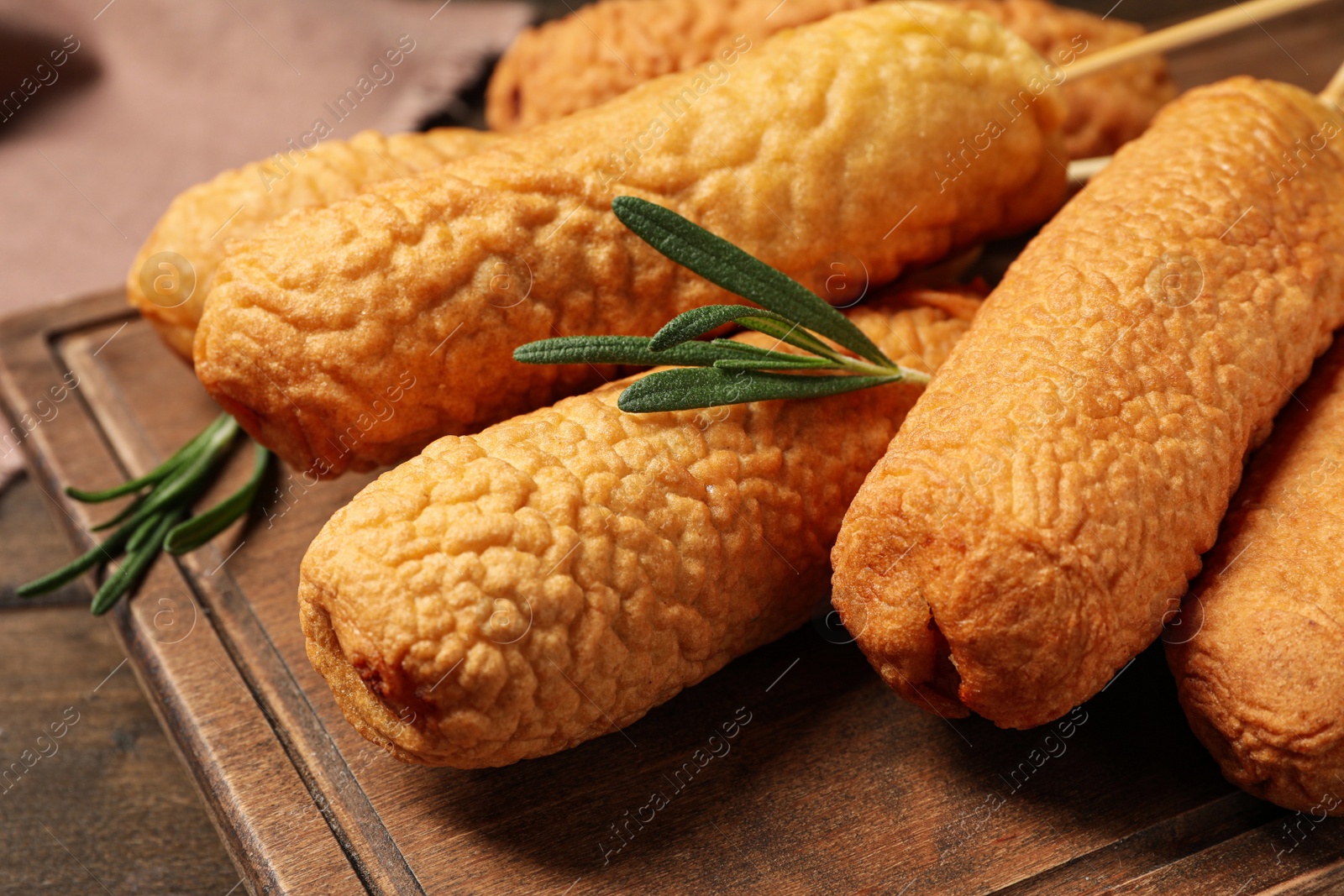 Photo of Delicious deep fried corn dogs on wooden board, closeup