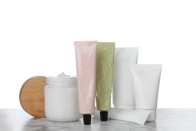 Photo of Set of cosmetic products in jar and tubes on marble table against white background