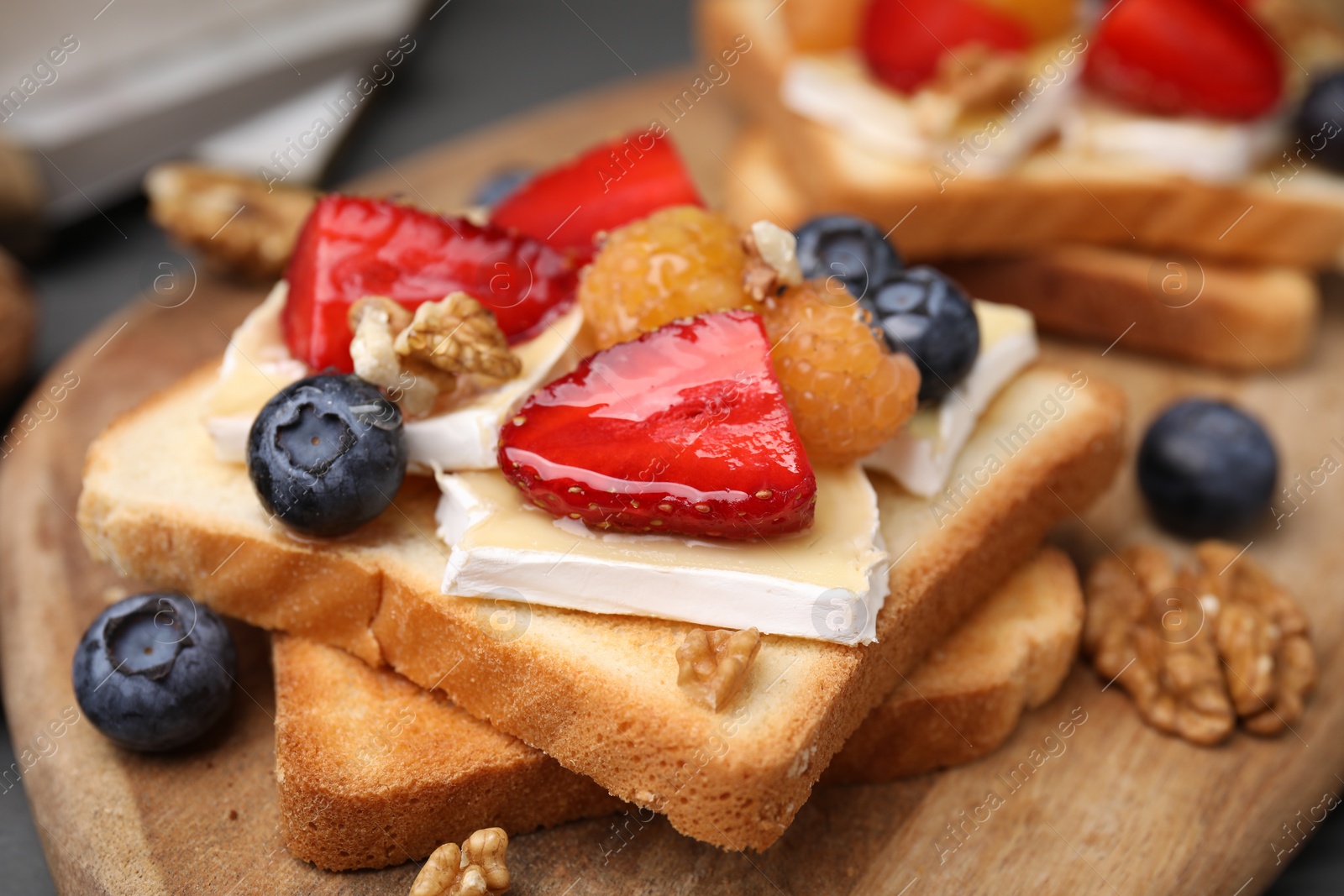 Photo of Tasty sandwiches with brie cheese, fresh berries and walnuts on table, closeup