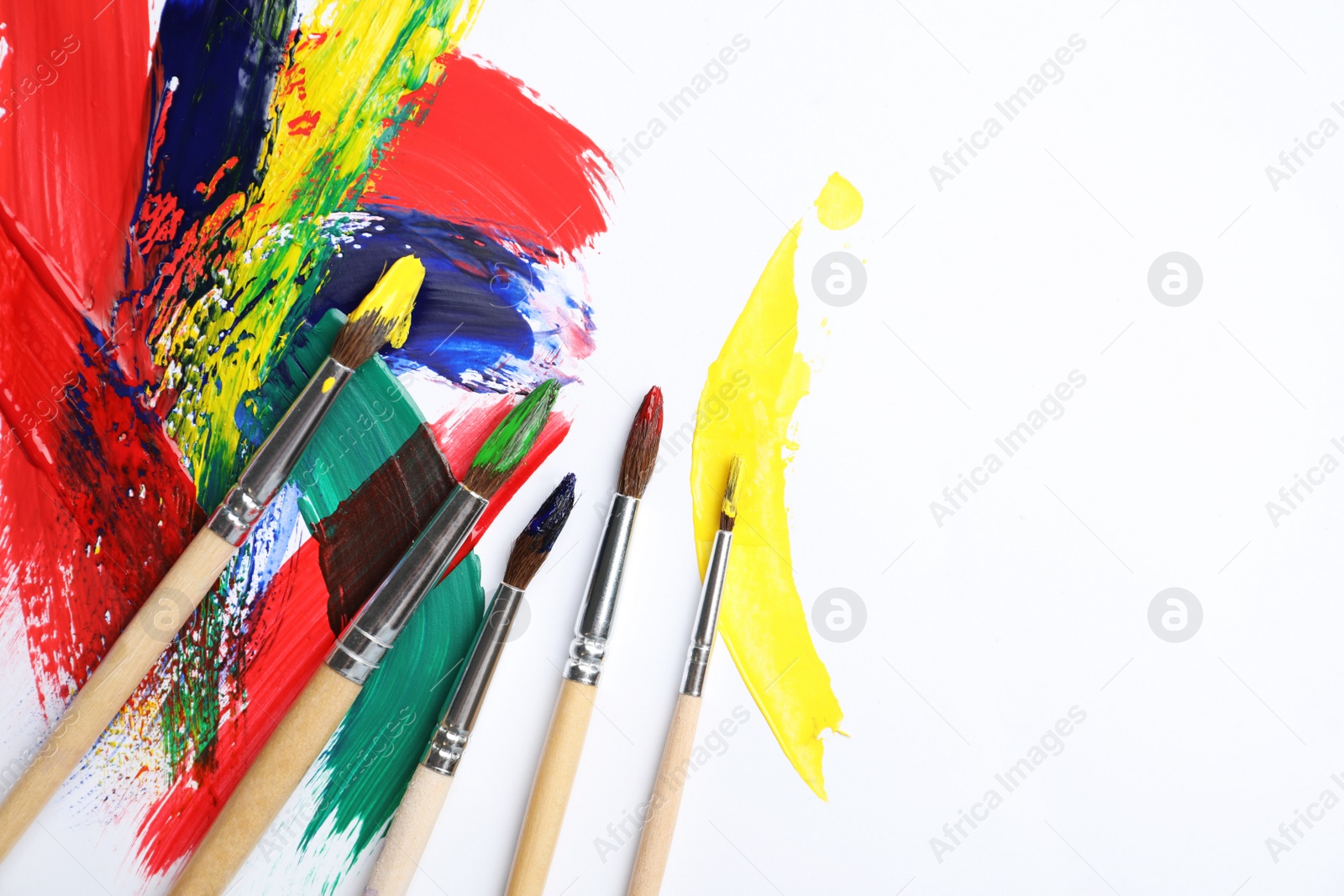 Photo of Brushes with different paints and strokes on white background, flat lay. Space for text