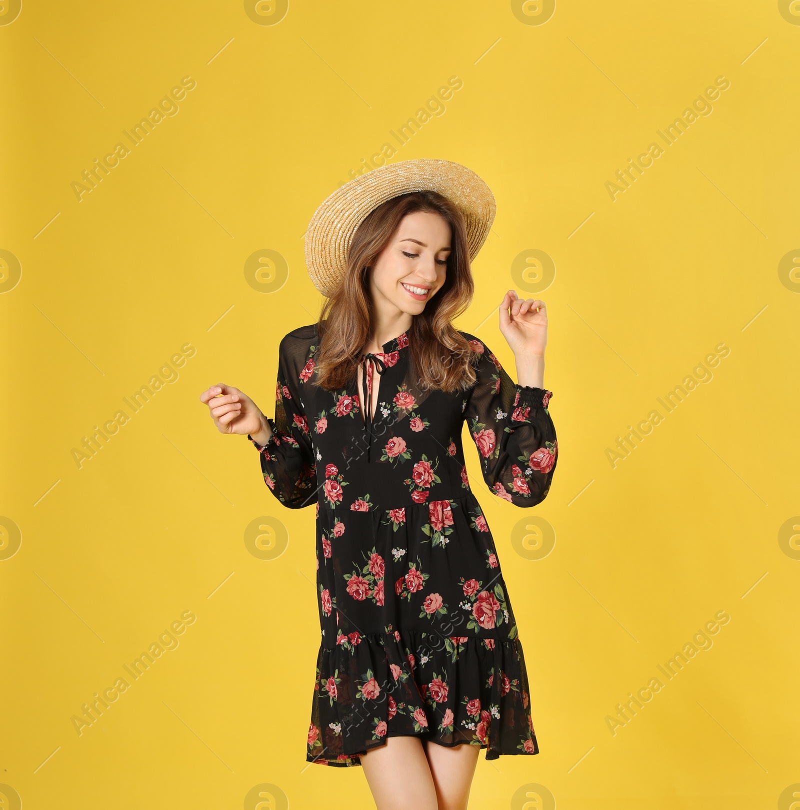 Photo of Young woman wearing floral print dress and straw hat on yellow background