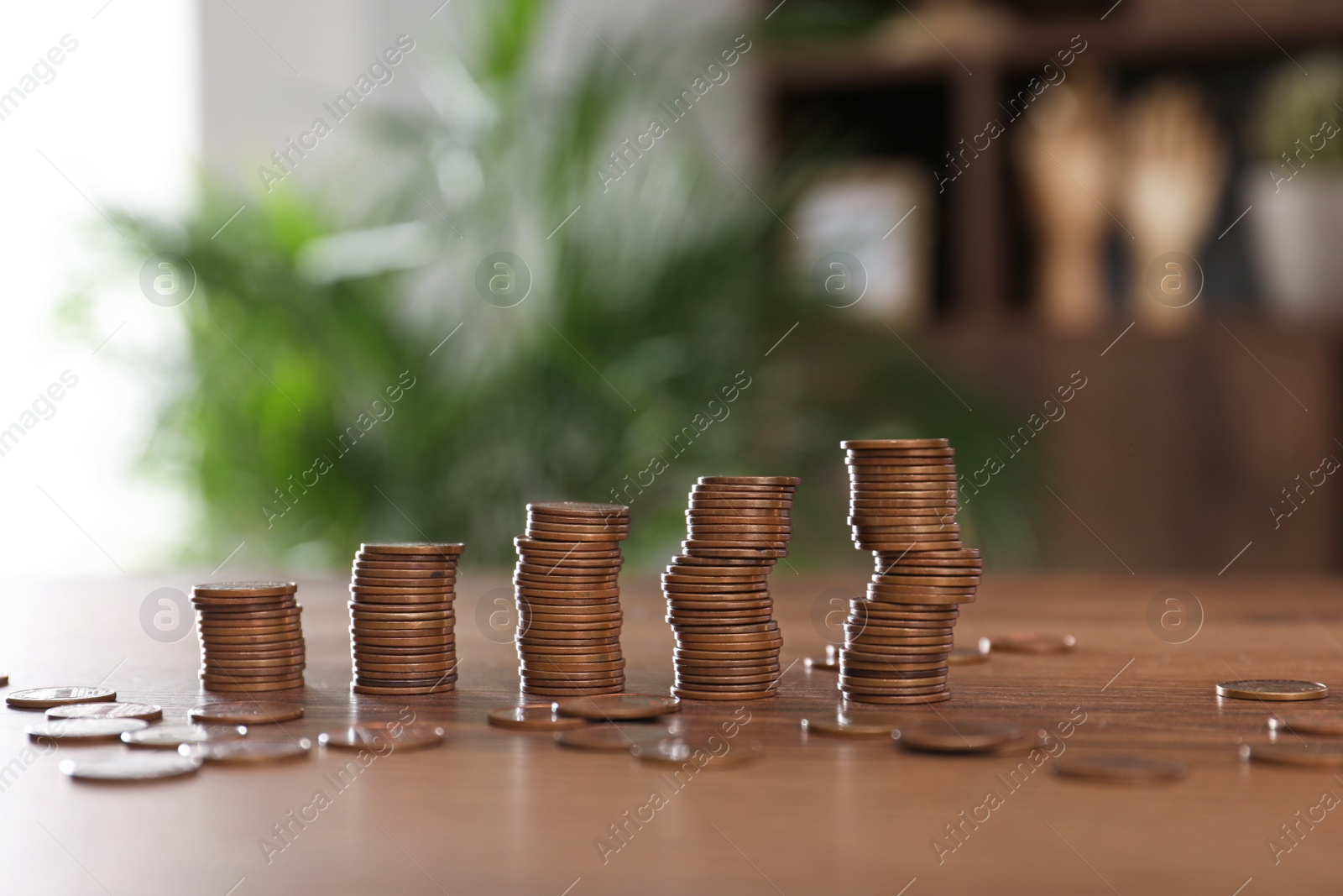 Photo of Stacks of coins on wooden table against blurred background