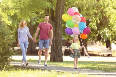 Happy family with colorful balloons in park on sunny day