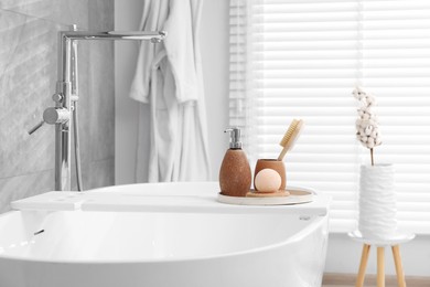 Photo of Different personal care products and accessories on bath tub in bathroom