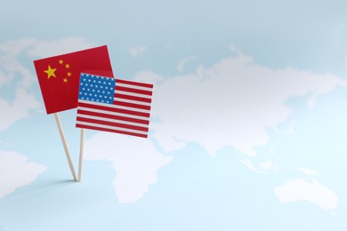 Photo of American and Chinese flags on world map, space for text. Trade war concept