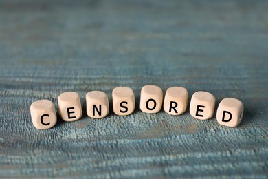 Photo of Wooden cubes with word Censored on light blue table