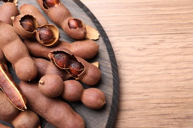 Delicious ripe tamarinds on wooden table, top view. Space for text