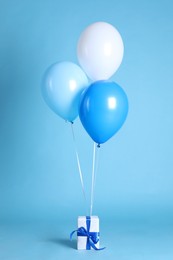 Photo of One gift box and balloons on light blue background