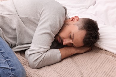 Photo of Upset man lying on bed. Loneliness concept