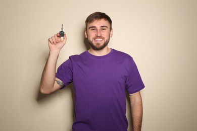 Photo of Happy young man with car key on color background. Getting driving license