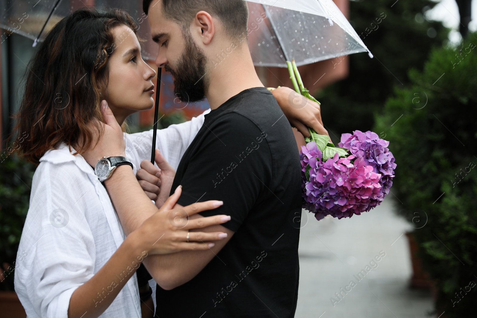 Photo of Young couple with umbrella enjoying time together under rain on city street