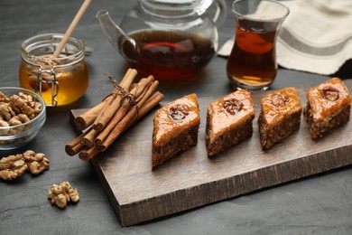 Photo of Delicious sweet baklava with walnuts and cinnamon on black table