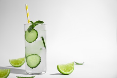 Glass of tasty fresh cucumber water with mint and sliced lime on white background, space for text