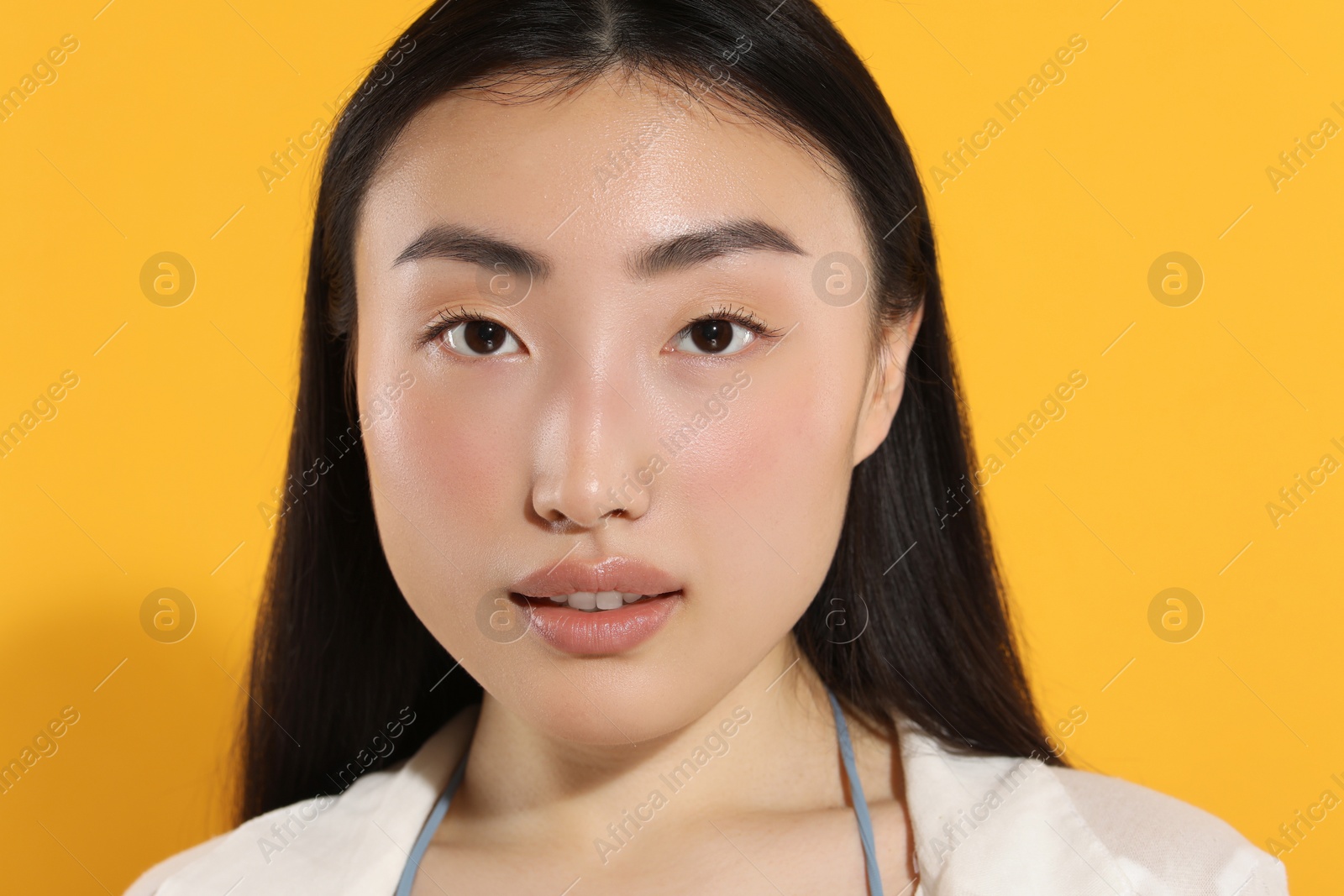 Photo of Beautiful young woman on orange background, closeup