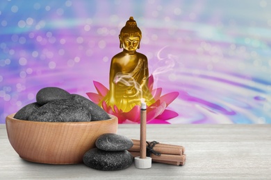 Composition with smoldering incense stick on wooden table and Buddha figure on background