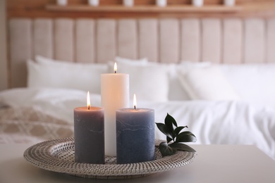 Tray with burning candles and leaves on white table indoors. Space for text