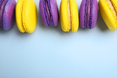 Photo of Delicious colorful macarons on light grey background, flat lay. Space for text