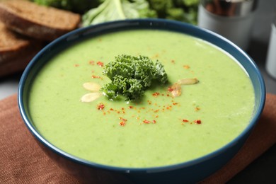 Photo of Tasty kale soup with pumpkin seeds on table, closeup