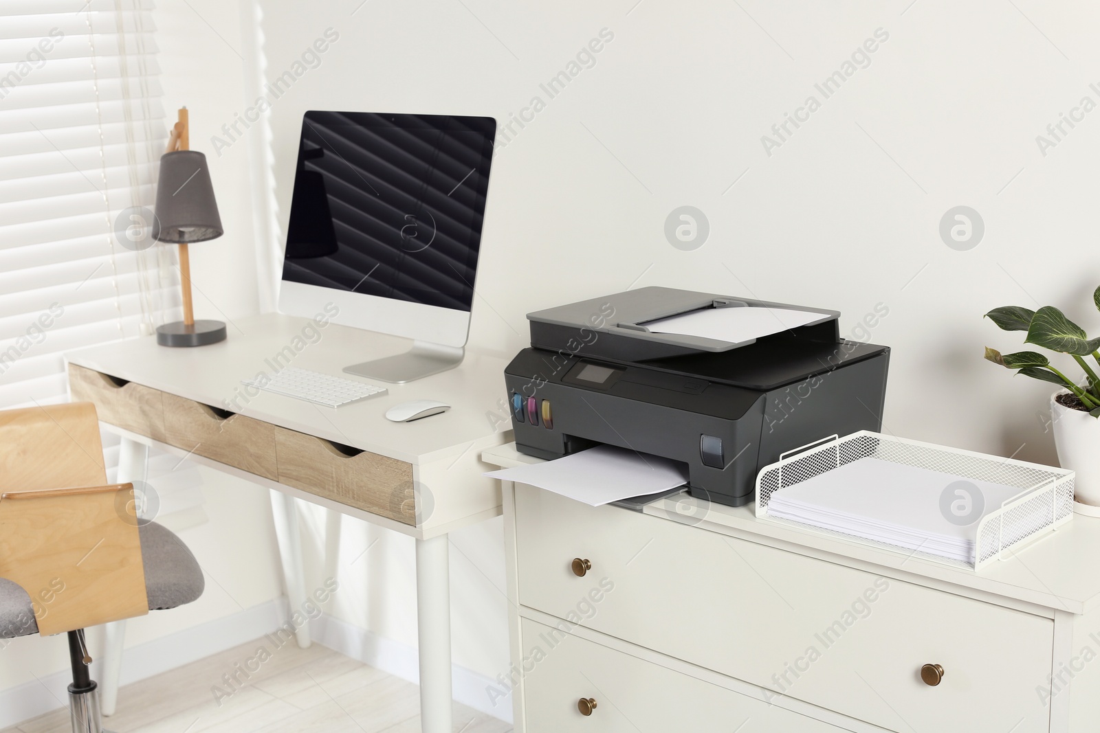 Photo of Stylish workplace with modern computer, printer and lamp