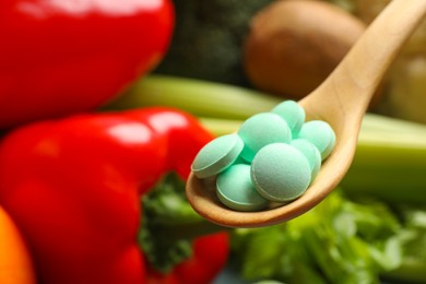 Dietary supplements. Spoon with pills over food products, closeup. Space for text