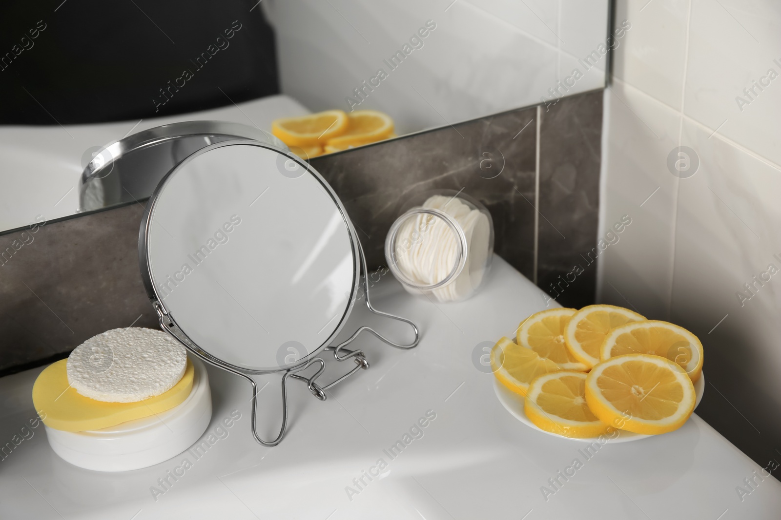 Photo of Lemon face wash. Fresh citrus fruits, personal care products and mirror on sink in bathroom