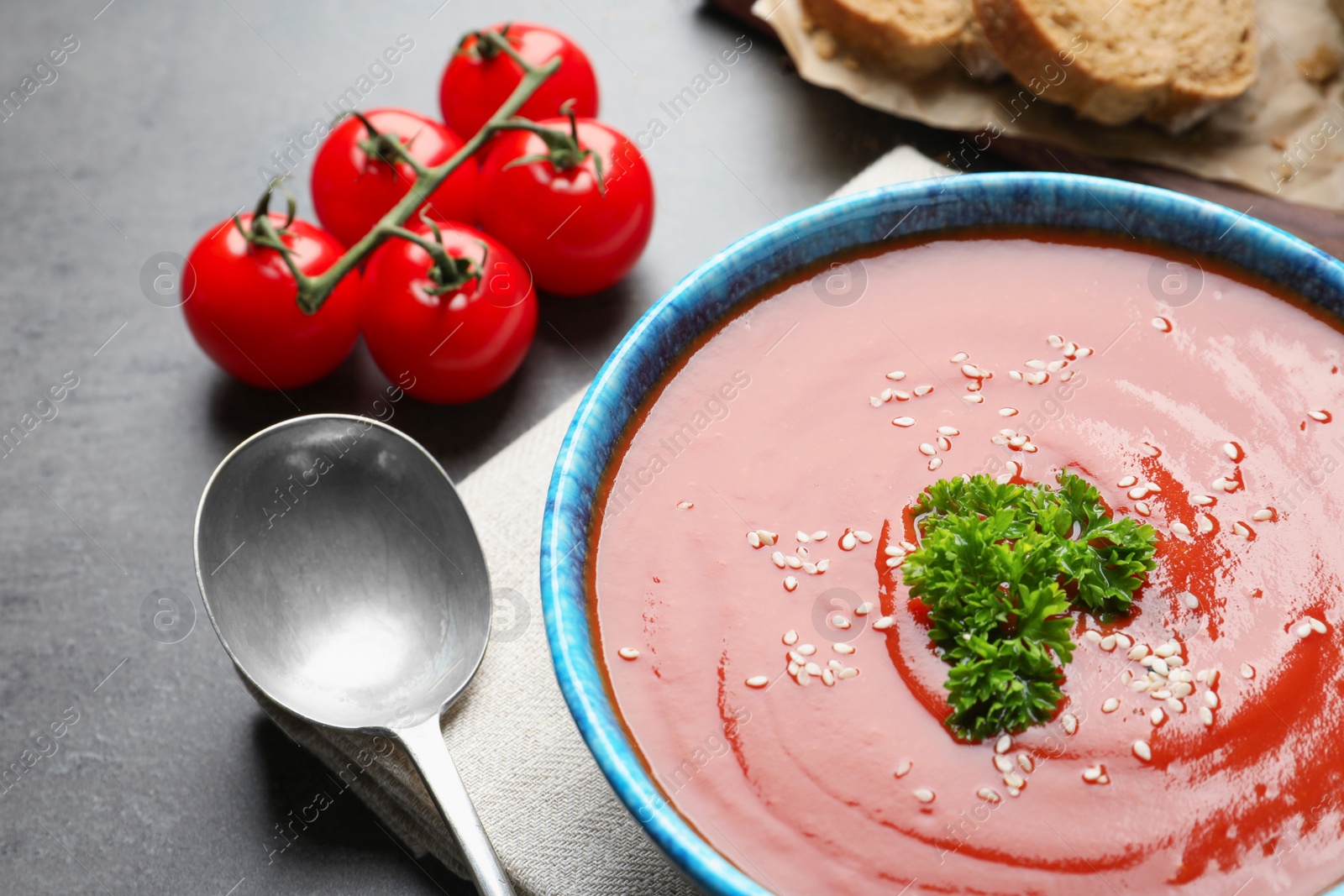 Photo of Bowl with fresh homemade tomato soup on grey table