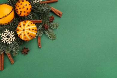Photo of Flat lay composition with pomander balls made of fresh tangerines and oranges on green background. Space for text