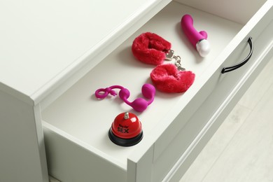 Different modern sex toys in open wooden drawer