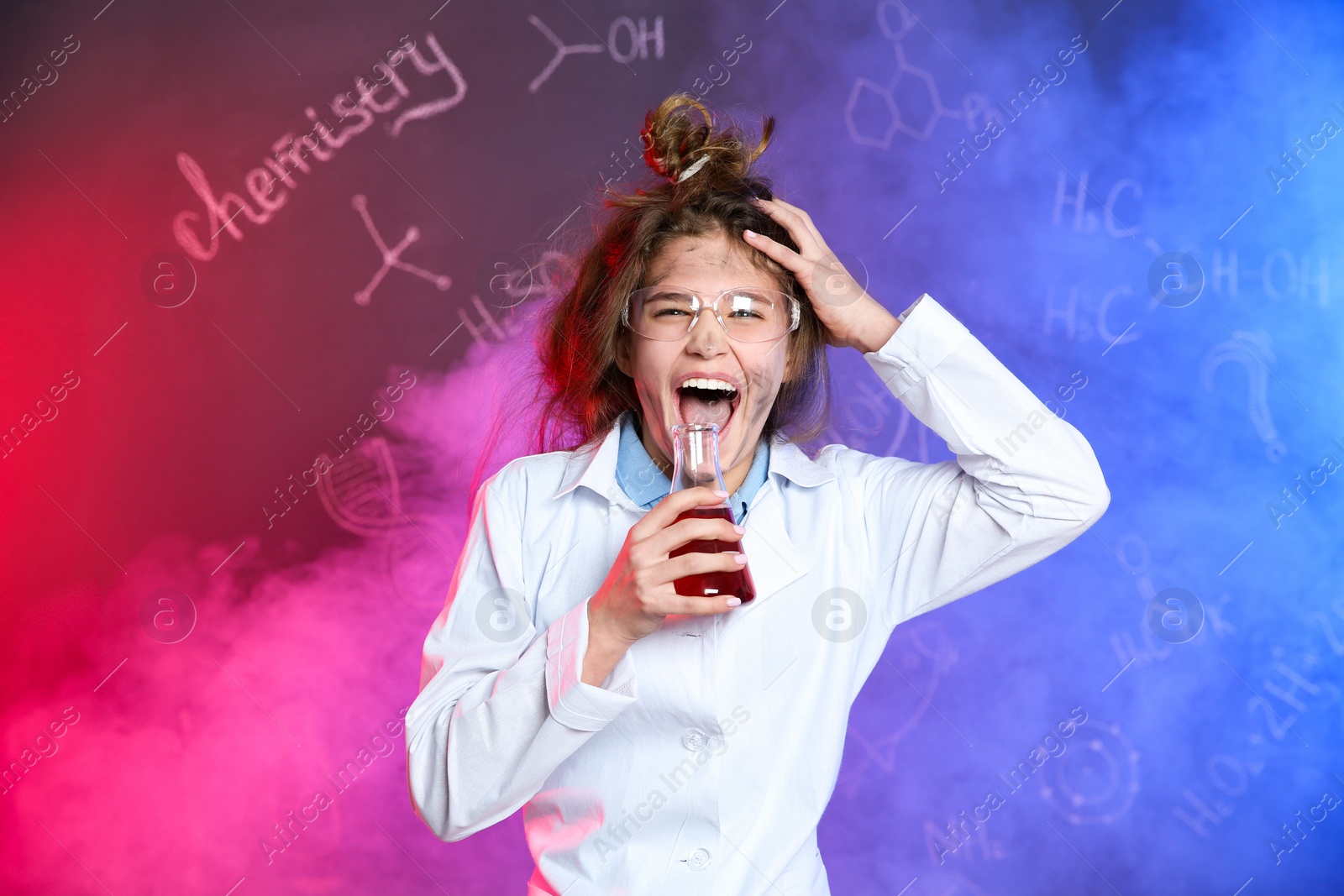 Photo of Emotional pupil holding conical flask in smoke against blackboard with chemistry formulas