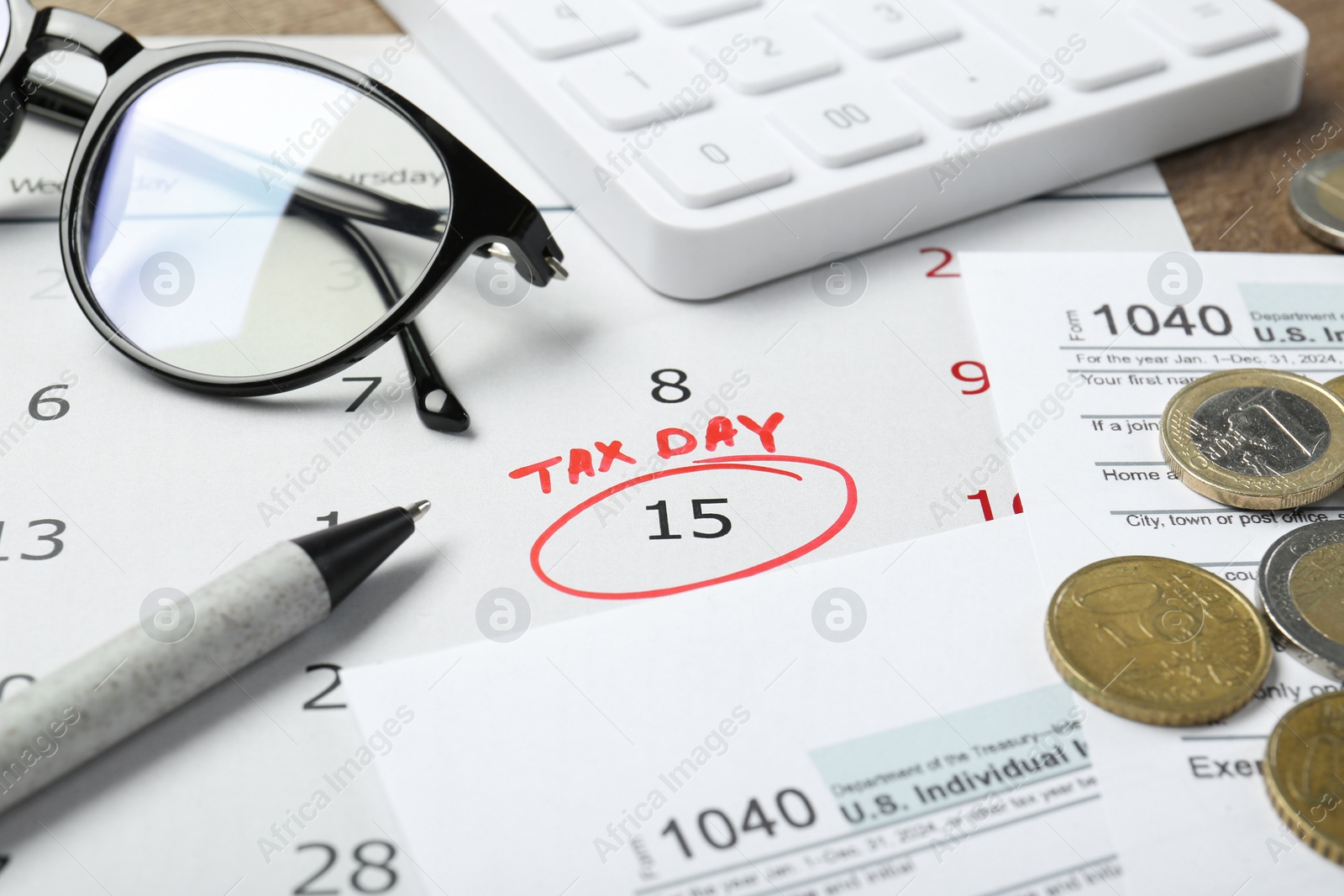 Photo of Calendar with date reminder about tax day, documents, pen, coins, glasses and calculator on table, closeup